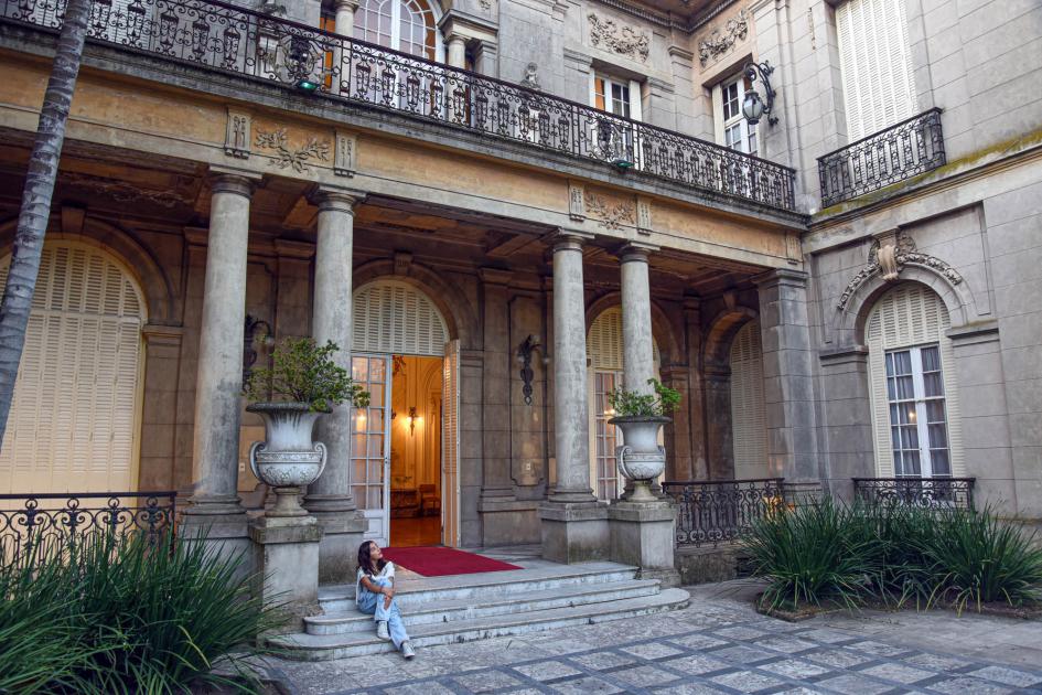 La exhibición puede visitarse hasta marzo de 2025 en el Palacio Taranco Patio del Palacio Taranco; una joven está sentada en una escalinata