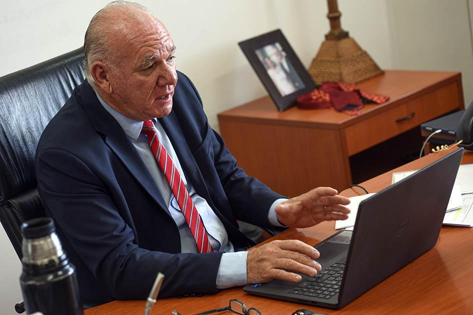 Verri expuso en el segmento sobre transición energética en Ambición América Latina Verri mira una laptop en la mesa de su despacho. Está sentado en un sillón negro.