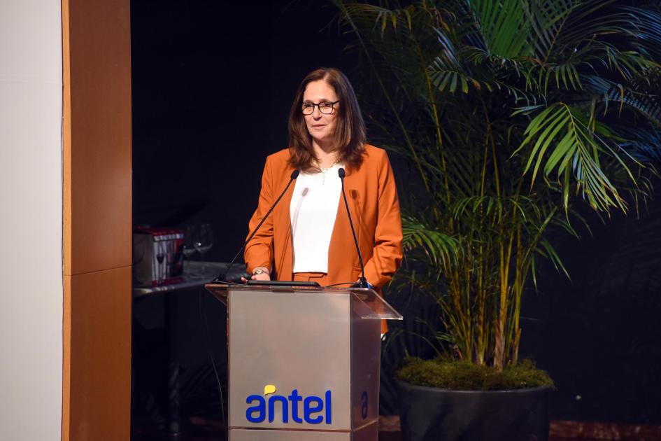 Ministra Elisa Facio Facio habla desde un atril con el logo de Antel; detrás, plantas