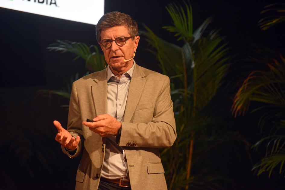 Gerente general de Antel, Humberto Roca Roca habla sobre un escenario; detrás, plantas y el borde de una pantalla