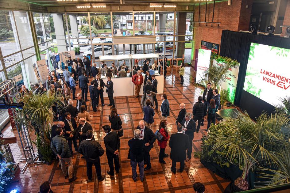 Vista aérea del hall del auditorio; se ven personas, pantallas y plantas