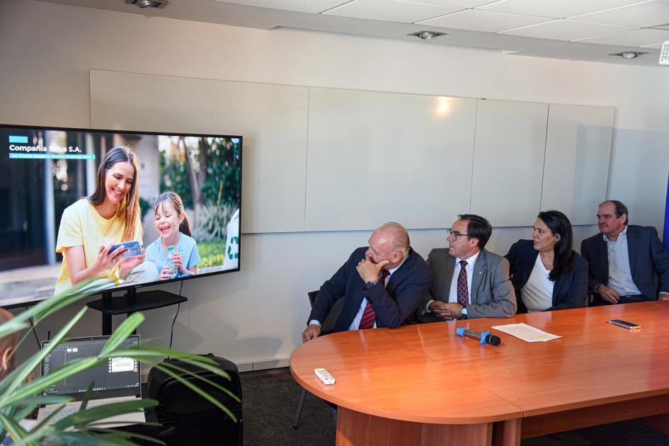 Las postulaciones para el premio son colectivas y se presentan hasta el 21 de abril Autoridades miran una pantalla en la que una mujer y una niña miran un celular