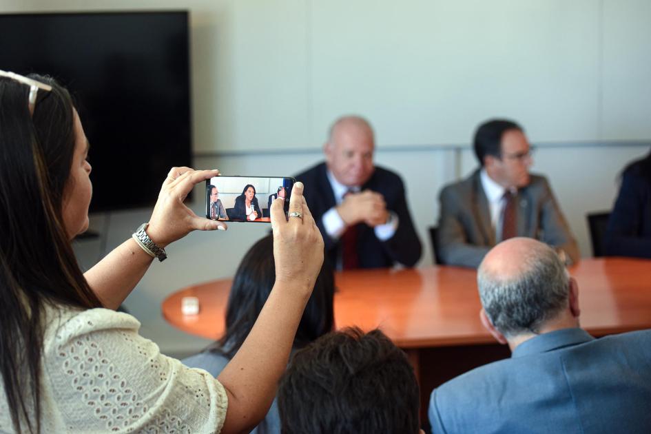 En primer plano se ve a una mujer que enfoca en su celular a Sánchez; de fondo, Verri y Bouvier