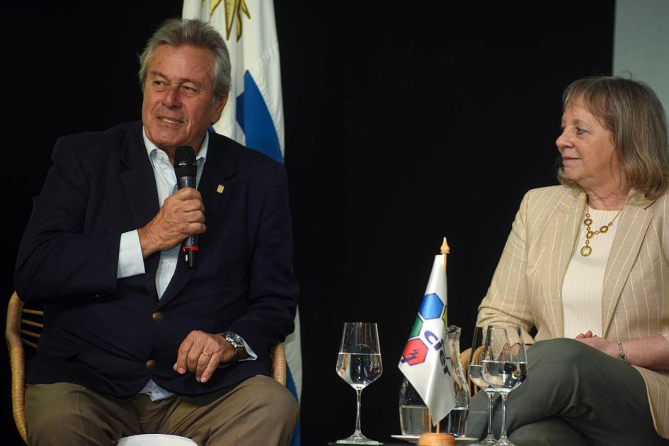 Intendente de Maldonado, Enrique Antía Antía habla, sentado; a su lado, Emaldi; detrás, bandera uruguaya