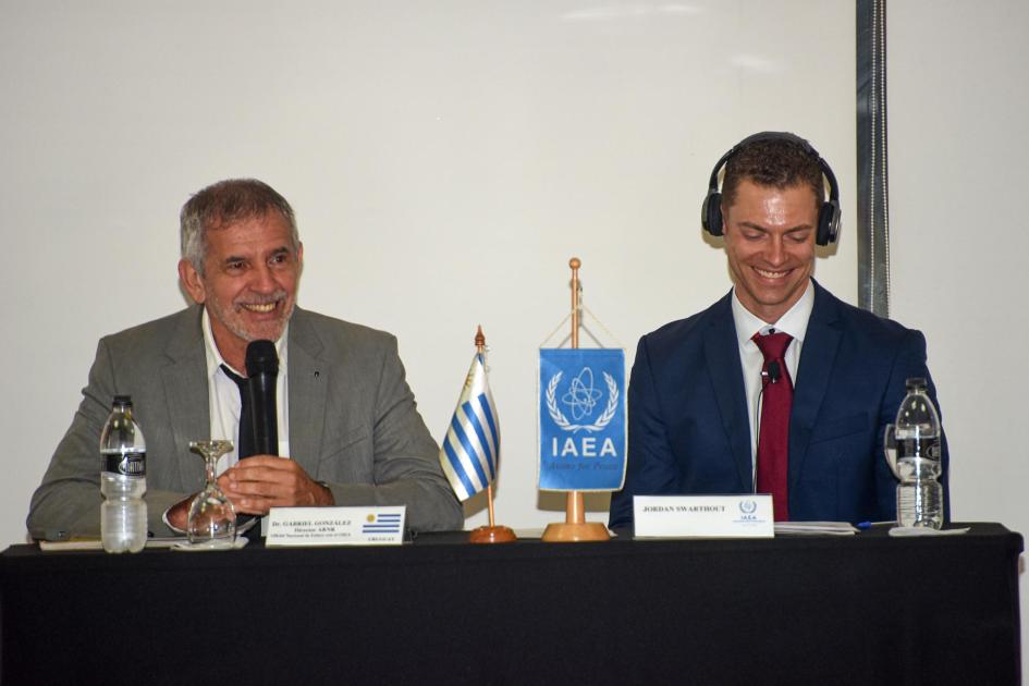 Director de la ARNR y experto del OIEA en la mesa de apertura Dos personas, sentadas en una mesa