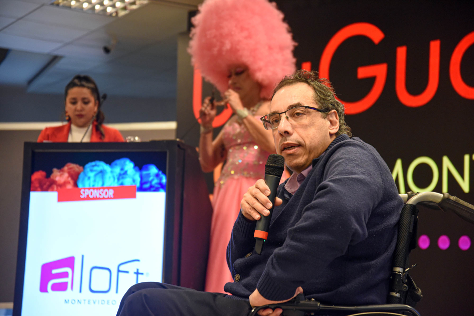 Ministro Pablo Menoni Menoni habla con un microfóno; detrás, maestras de ceremonia