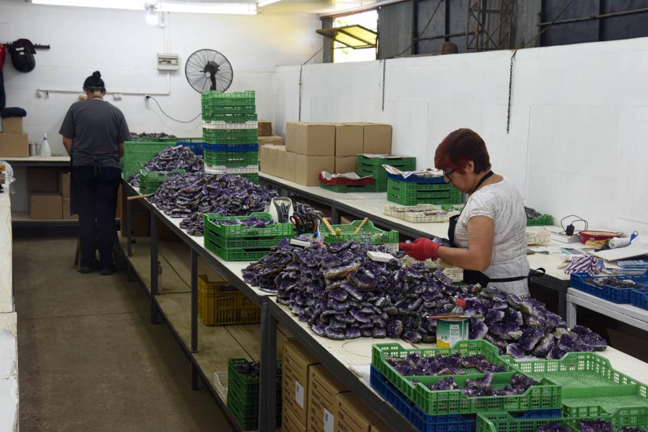 Mujer trabajadora del sector minero, en Artigas Mujer trabaja en una mesa con piedras; al fondo, otra persona