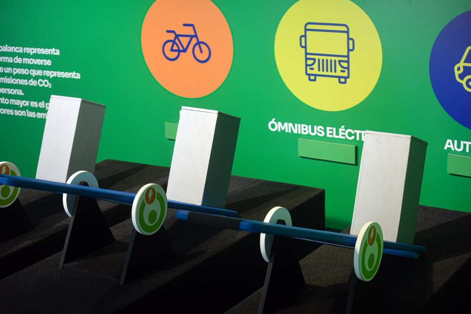 Propuesta didáctica del stand del MIEM, centrado en la movilidad sostenible Pared con textos y vehículos, en colores; más cerca, prismas en una línea