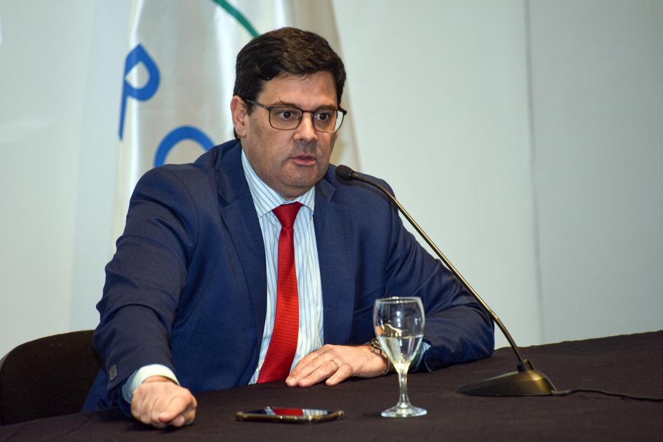 Director nacional de Energía, Fitzgerald Cantero. Habla el director Cantero; detrás hay una bandera blanca; en la mesa, una copa con agua