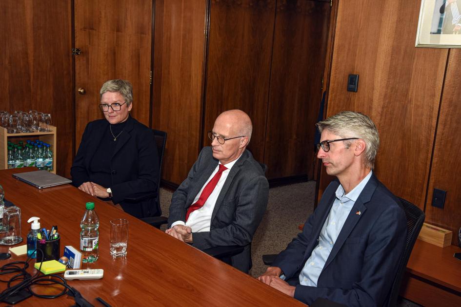 Parte de la delegación alemana Dos hombres y una mujer, sentados alrededor de una mesa de madera