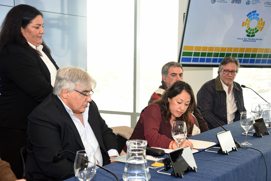 Firma del convenio para la creación del PTE Cardona, firma, en mesa de autoridades; una mujer está de pie