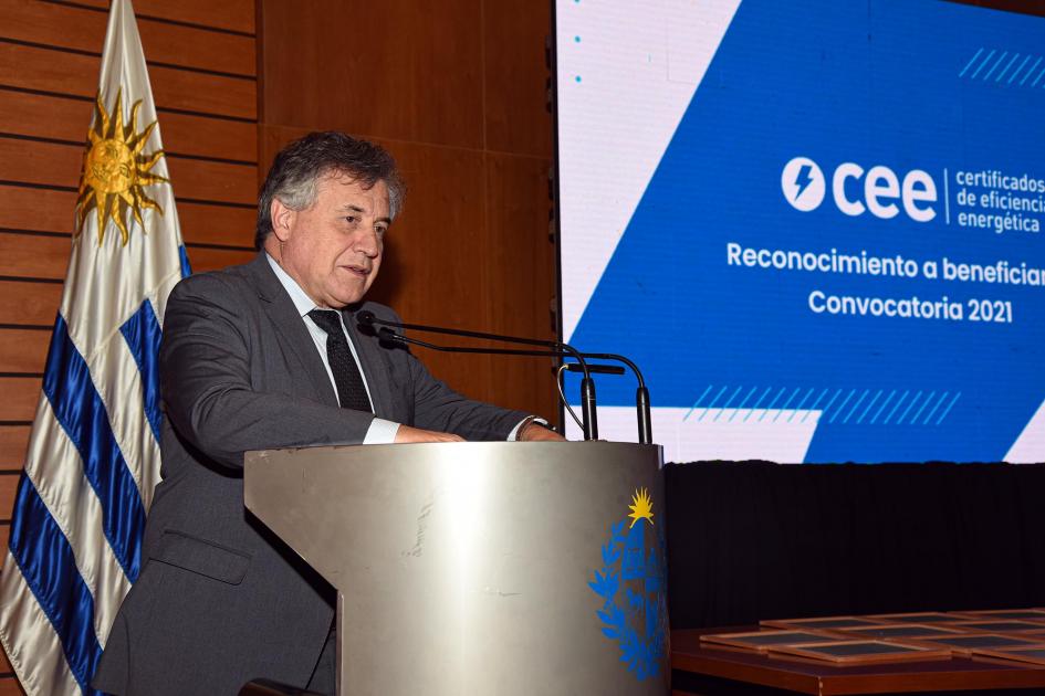 Ministro Omar Paganini Paganini habla en un atril; detrás la bandera uruguaya y una pantalla