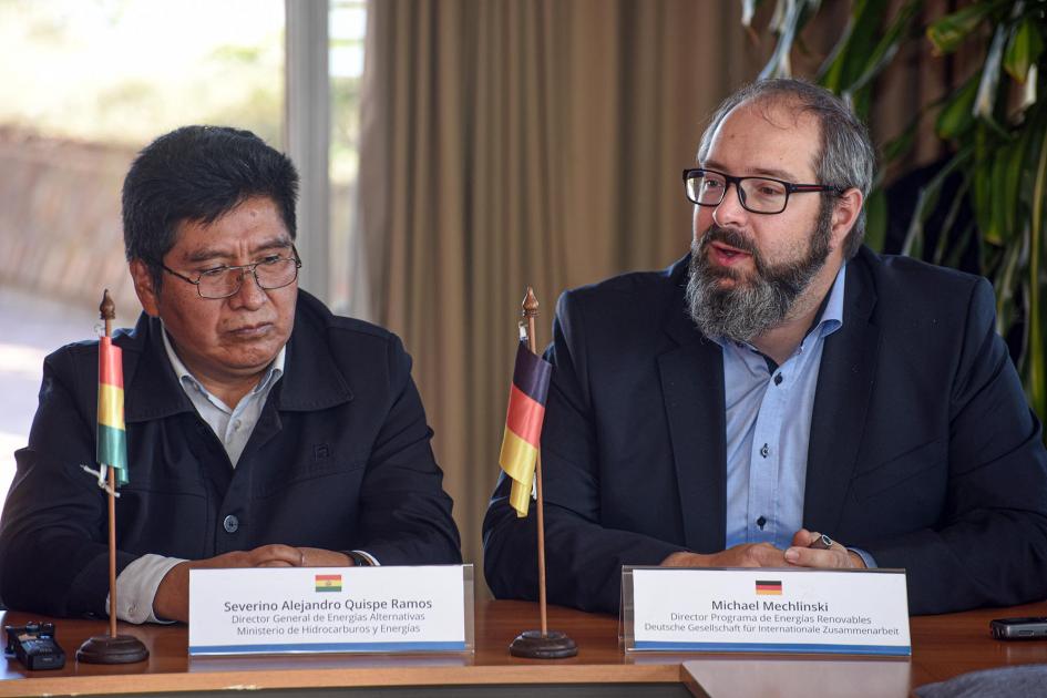 Director del Programa de Energías Renovables de la GIZ, Michael Mechlinski Mechlinski junto a Quispe; tienen cartelitos con sus nombres y banderas en la mesa