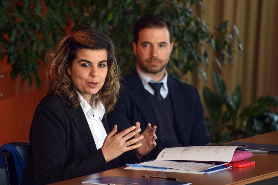 Parte del equipo de funcionarios del MIEM Un hombre y una mujer, integrantes del MIEM, en una mesa lateral; detrás hay plantas