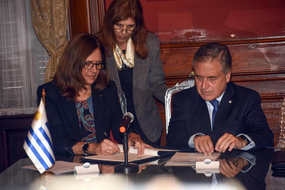 Ministra Facio firma junto al ministro Paganini; detrás, una funcionaria..