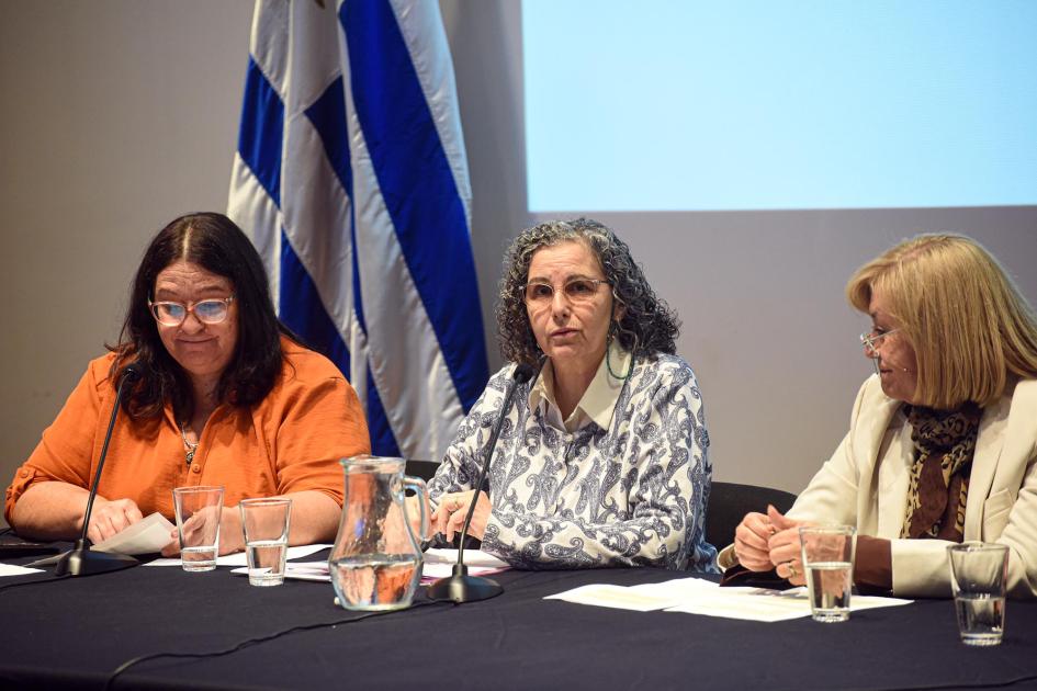 Tres mujeres en la mesa de especialistas; al lado, bandera uruguaya