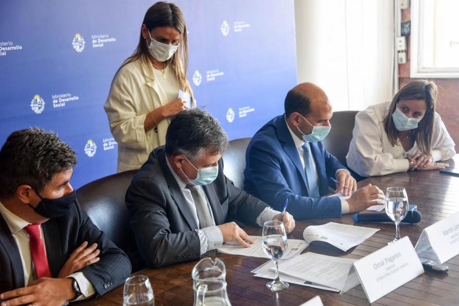Autoridades firman el convenio Autoridades firman el convenio; detrás, una mujer les alcanza los documentos
