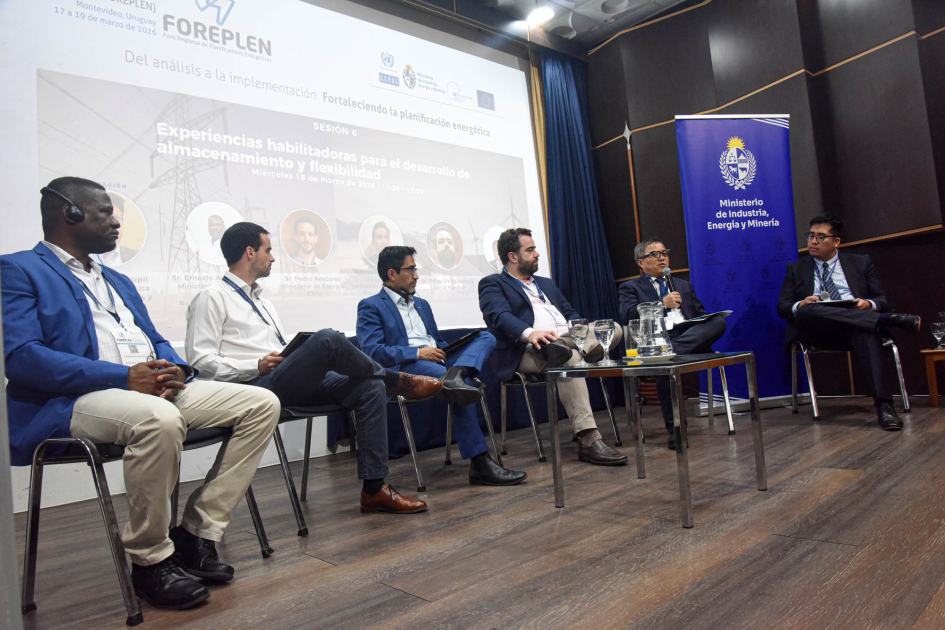 Personas sentadas en un escenario; detrás, pantalla con imagen institucional y banner del MIEM
