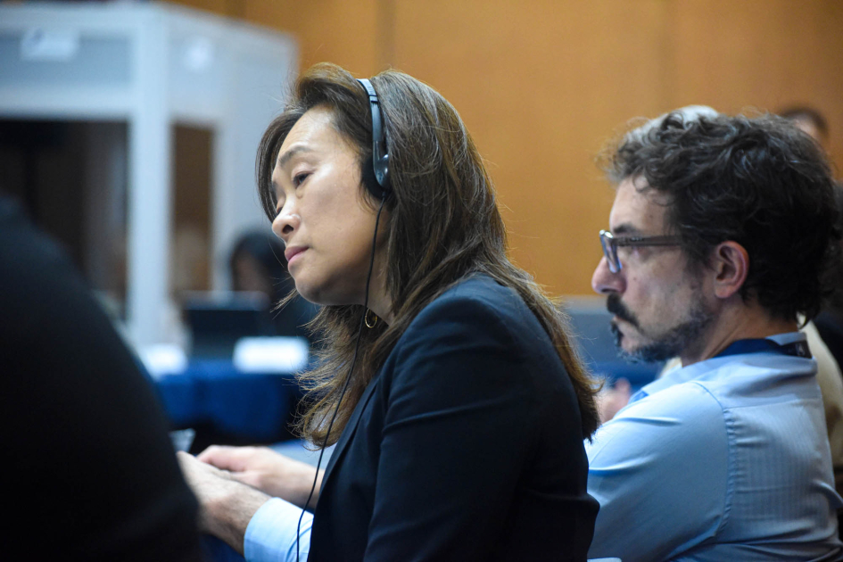 Hombre y mujer en una mesa; ella escucha con auriculares