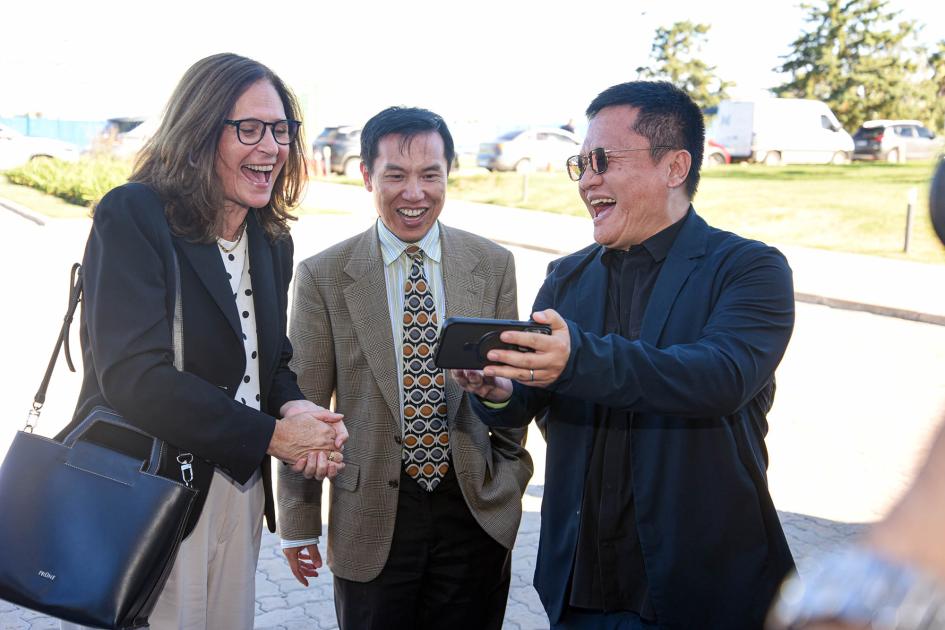 Ministra Facio sonríe junto a dos representantes chinos, mirando un celular