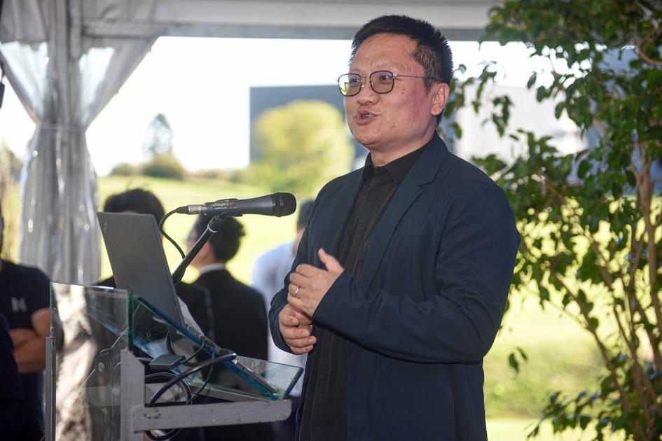 CEO de BGI Group, Yin Ye El CEO de la empresa habla desde un atril; debajo, público y plantas