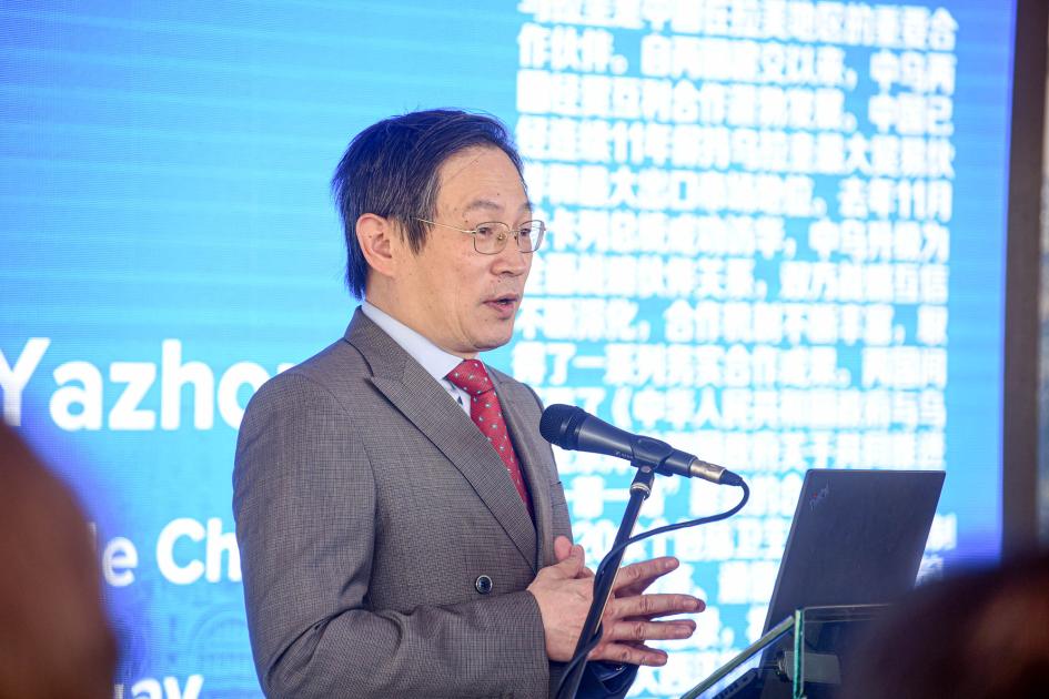 Embajador Huang Yazhong habla desde un atril; detrás, una pantalla