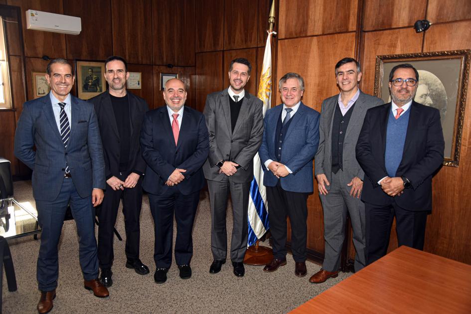 El ministro recibió a la delegación en el MIEM Grupo de siete hombres; detrás hay una bandera uruguaya