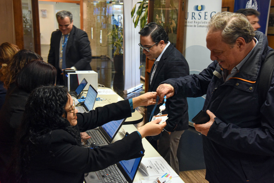 Personas reciben sus identificaciones en la mesa de acreditaciones