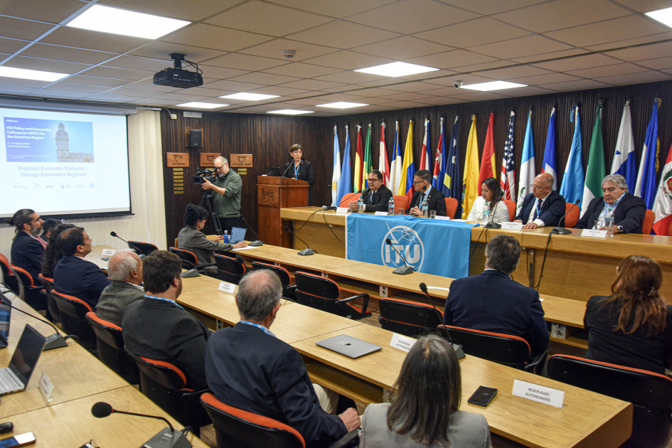 Al fondo, mesa de autoridades; detrás, banderas; más cerca, público