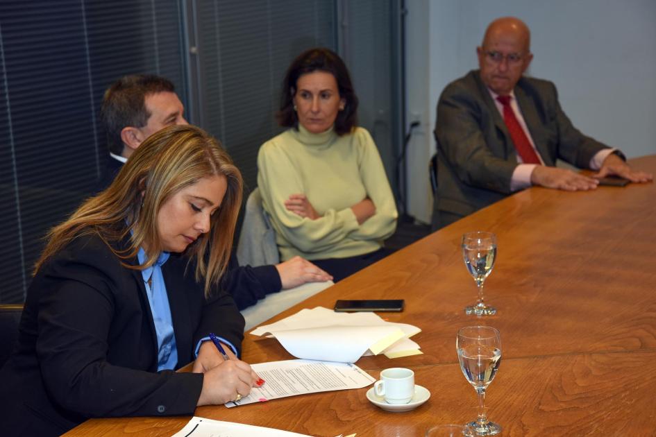 Directora Pecoy firma; a su lado, dos hombres y una mujer