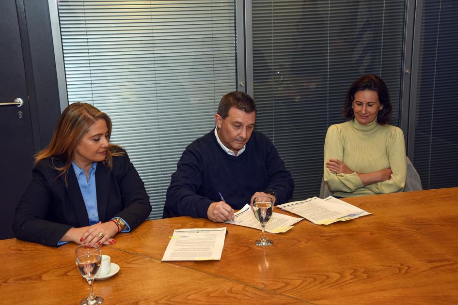 Representante de Rivera firma; a su lado, Pecoy y otra mujer