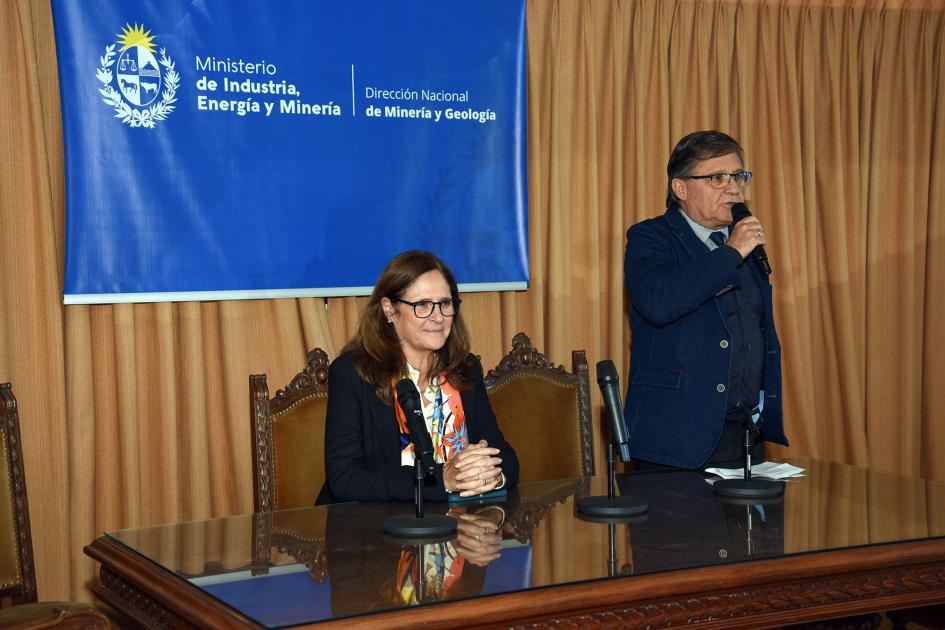 Director nacional Marcelo Pugliesi Director Pugliesi, de pie junto a Facio, sentada; arriba, banner de MIEM-Dinamige