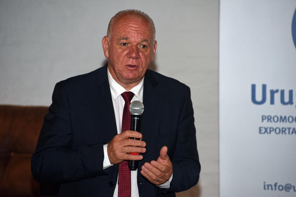 Ministro interino Walter Verri Verri, con un micrófono en la mano; al lado, se ve un fragmento de banner de Uruguay XXI