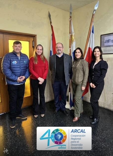 Reunión con el decano de la Facultad de Química, Álvaro Mombrú, y con la la Dra. Mariella Terán Cinco personas ubicadas para la foto, de pie, con banderas de fondo