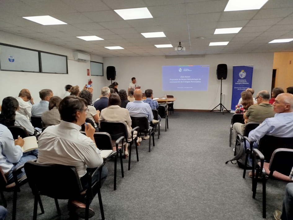 Presentación del nuevo modelo de contratación. Público sentado de espalda. Al fondo se ve una pantalla y banner institucional