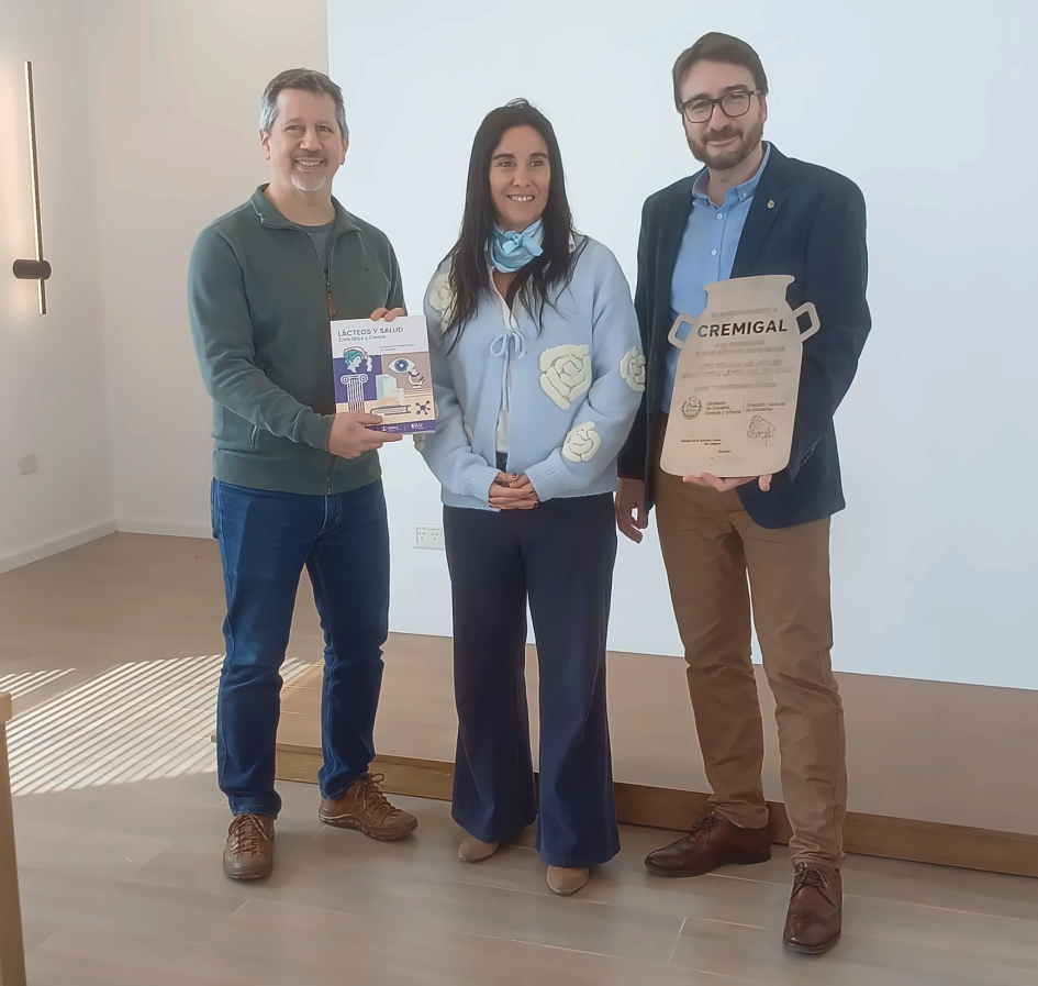 Director Míguez, de pie, con un hombre y una mujer; sostienen materiales de Cremigal