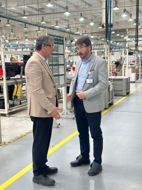 El director Adrián Míguez visitó la empresa autopartista Director y otro hombre dialogan