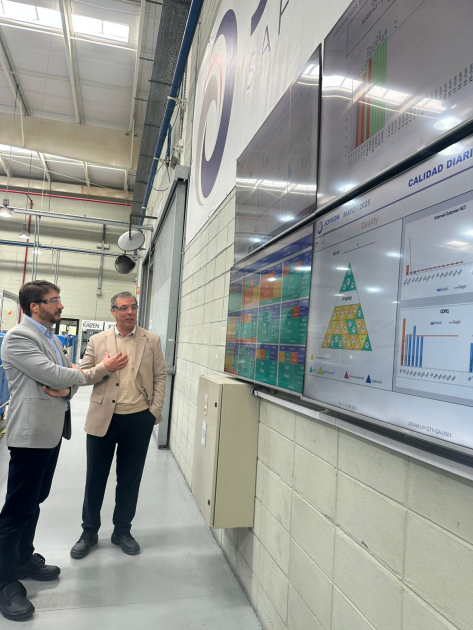 Visita a empresa autopartista Joyson Director Míguez dialoga con otro hombre mientras observan la planta