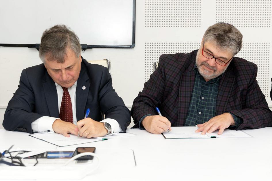 Ministro firmando acuerdo junto a Jon Medved