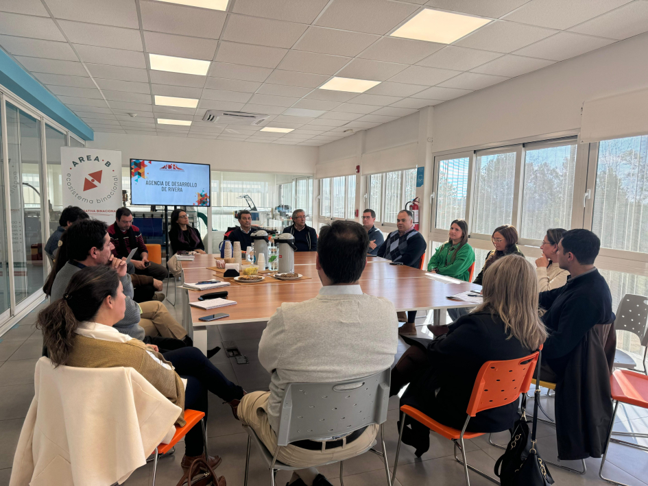 Presentación de Área B Grupo de personas, alrededor de una mesa, en una oficina con ventanales