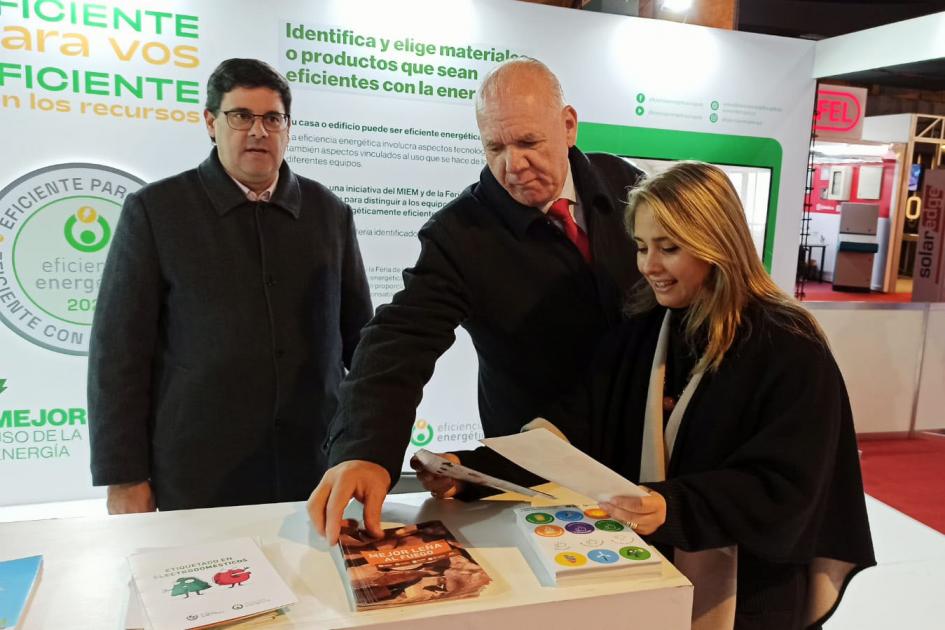Las autoridades del MIEM se informaron sobre eficiencia energética con los materiales del stand de la institución Verri, Pecoy y Cantero miran folletos en el stand del MIEM