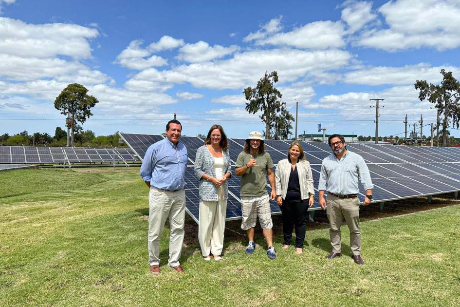 Autoridades y representantes de la empresa junto a paneles fotovoltaicos en un día con algunas nubes