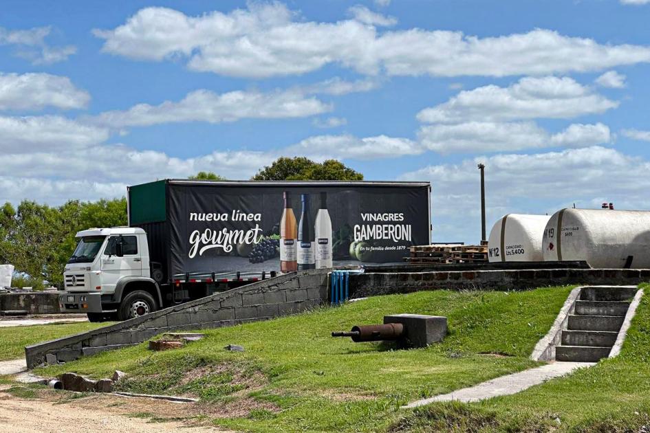 Camión, en un espacio exterior, con fotos de vinagres; dice "Línea Gourmet"