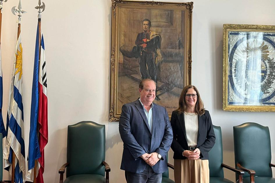 Ministra Elisa Facio e intendente Wilson Ezquerra Ministra e intendente posan, de pie, bajo un cuadro de Artigas; a su lado, sillas y pabellones