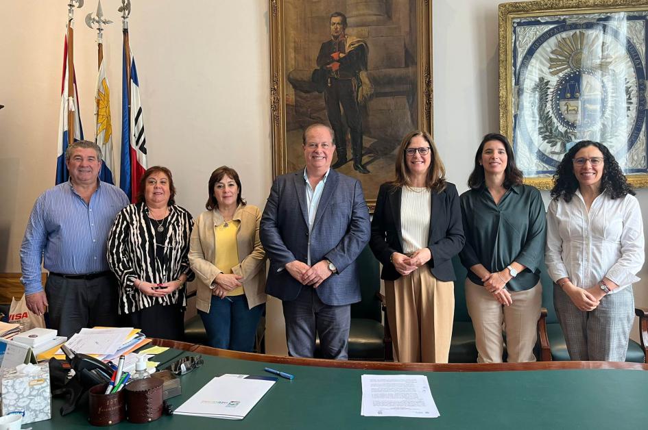 Equipos de trabajo del MIEM y de la Intendencia de Tacuarembó Varias personas posan de pie, detrás de una foto y bajo un cuadro de Artigas; al lado, pabellones