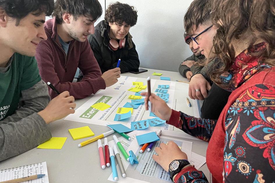 Adolescentes y jóvenes, sentados, toman notas, entre papeles