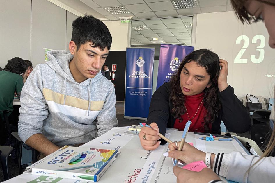 Dos adolescentes (un varón y una chica) trabajan en una mesa, sentados