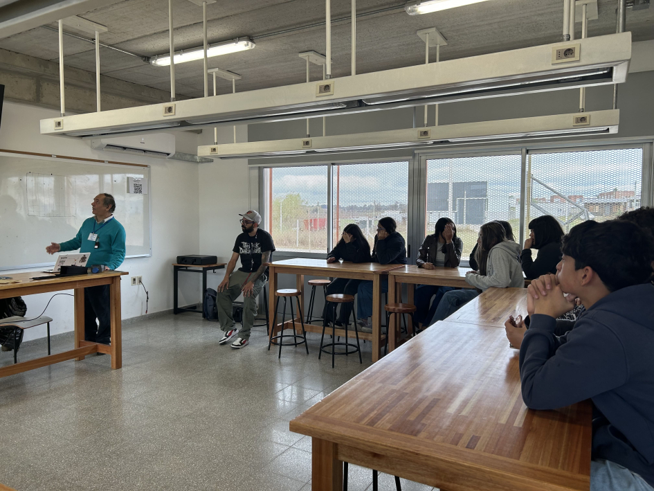 Salón de clase; adolescentes, sentados en mesas; frente a ellos, experto de ARNR