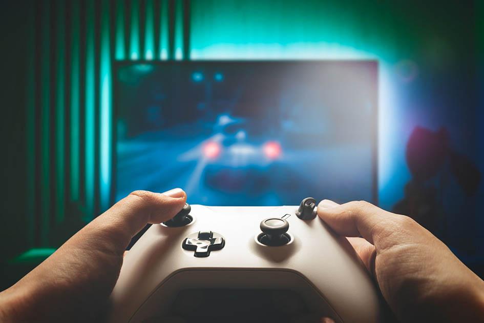 Convocatoria Videojuegos 2024 Foto de manos que juegan con un joystick frente a un televisor