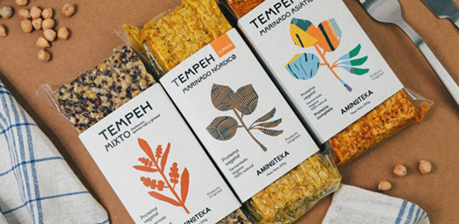 Variedades de tempeh de Aminoteka Envases con dibujos de plantas de colores sobre una madera